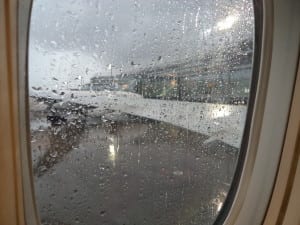 Janela do avião antes do embarque em dia de chuva